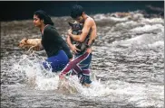  ?? MARIO TAMA / GETTY IMAGES ?? Residents carry dogs to dry land in Hilo, Hawaii, on Friday after briefly playing in flood waters brought on by heavy rains from Hurricane Lane.