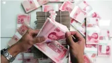  ?? — Reuters ?? A woman counts Chinese yuan notes at a bank in Beijing.