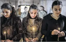  ?? CENGIZ YAR / ASSOCIATED PRESS ?? Three women attend Christmas Eve Mass on Saturday in the Assyrian Orthodox church of Mart Shmoni in Bartella, Iraq. Government forces recently retook Bartella from the Islamic State, which seized the town in 2014.