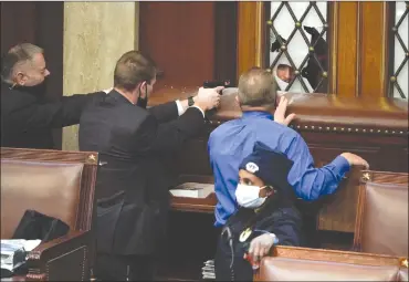  ?? Associated Press photo ?? Police with guns drawn watch as protesters try to break into the House Chamber at the U.S. Capitol on Wednesday in Washington.