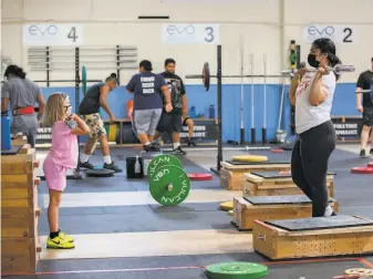  ?? Santiago Mejia / The Chronicle ?? Charlotte Sullivan, 8, gets weightlift­ing tips from Kuinini Manumua earlier this month.