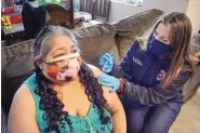  ?? JIM THOMPSON/JOURNAL ?? Sandoval County Fire and Rescue paramedic Shannon Farrell vaccinates Yolanda Trent in Trent’s home in Rio Rancho.