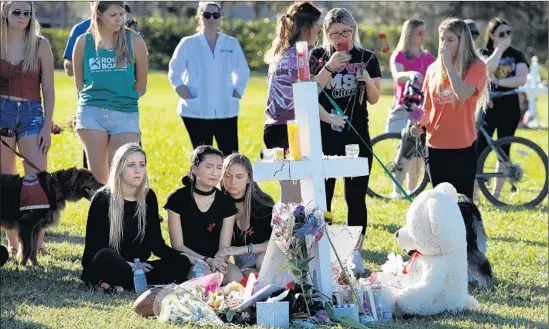  ?? Carolyn Cole Los Angeles Times ?? PEOPLE GATHER at a memorial in Parkland, Fla., for the victims of the school shooting. Of the 17 people killed in the attack, seven of them were 14 years old.