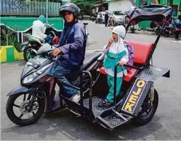  ?? Reuters ?? Hartanto, a disabled motorcycle taxi driver, carries a student passenger in Yogyakarta, Indonesia. Taxis are providing disabled people with sources of income in the country.