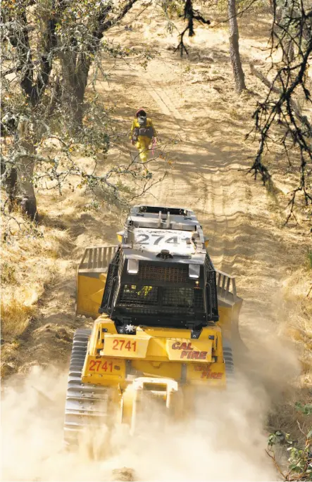  ?? Paul Kuroda / Special to The Chronicle ?? Above: A firefighte­r and a bulldozer head to the fire line in the small town of Oakville in the Napa Valley.