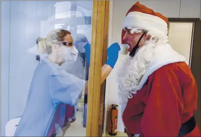  ?? JENS BUETTNER — DPA ?? Tessa Boulton, left, takes a swab test from Michael Kruse, dressed as Santa Claus, on Monday at a coronaviru­s testing center at the Helios Clinic in Schwerin, Germany.