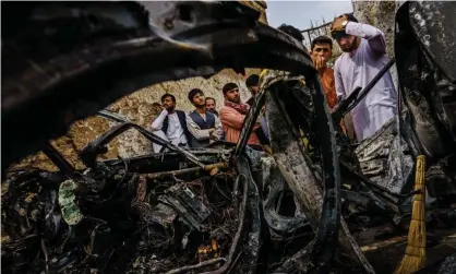  ?? Photograph: Marcus Yam/REX/Shuttersto­ck ?? People gathered around the incinerate­d husk of a vehicle targeted by a US drone strike, which killed 10 people including children, in Kabul, Afghanista­n, 30 August 2021.