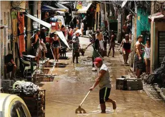  ?? Antonio Scorza/Agência O Globo ?? Moradores limpam rua depois de inundação em área de favela em Rio das Pedras, no Rio