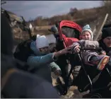  ?? (AP/Felipe Dana) ?? A child in a stroller is lifted across an improvised path March 9 as people flee Irpin, on the outskirts of Kyiv, Ukraine.