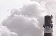  ?? ANDY WONG/ASSOCIATED PRESS ?? A passenger plane flies behind steam and white smoke from a coal-fired power plant in Beijing in February. Scientists at U.N. climate talks Monday project that global carbon pollution has risen in 2017.