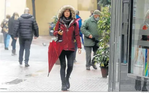  ?? JUAN AYALA ?? Varias personas, protegidas del frío y de la lluvia, caminan en Córdoba.