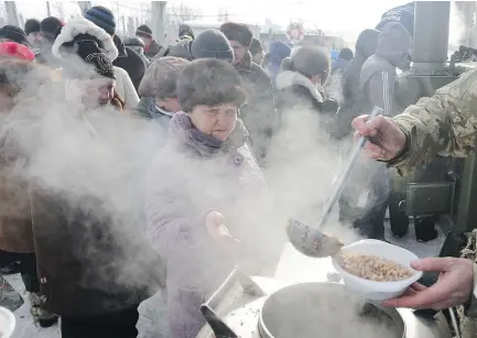  ?? — GETTY IMAGES ?? Rescue workers served food to local residents in the Ukrainian town of Avdiivka Wednesday as government forces and Russian-backed separatist­s exchanged fire for a fourth day.
