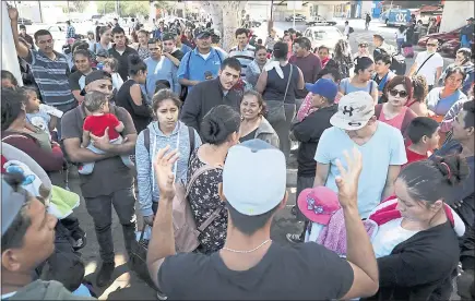  ?? PHOTOS BY THE ASSOCIATED PRESS ?? An organizer, foreground, speaks to families in Tijuana, Mexico, on Wednesday as they wait to request political asylum across the border in the United States. In Tijuana, Latin Americans fleeing drug violence in their countries are camped out and waiting to apply for asylum.