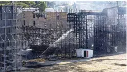  ?? ?? Firefighte­rs hose down a structure to extinguish a fire at the Cinecitta studios southeast of Rome. — AFP photos