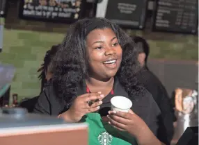  ?? TIM A. PARKER, FOR USA TODAY ?? Starbucks employee Adrienne Lemmons writes a name on a cup in Ferguson, Mo., on April 28, 2016, 20 months after the town was shaken by rioting in the aftermath of the police shooting death of Michael Brown. For the Whitehaven neigborhoo­d, which has endured the exodus of anchor stores like Macy’s, Jcpenney and others from Southland Mall in recent years, many feel the national coffee chain would inject hopes of a revival.