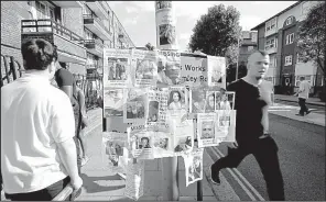  ?? AP/KIRSTY WIGGLESWOR­TH ?? Posters of missing people cover a sign Saturday near the site of the Grenfell Tower fire in London.