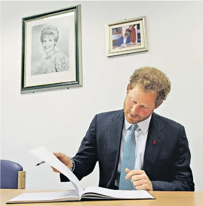  ??  ?? Prince Harry signs a visitors’ book beneath a photograph of his mother
