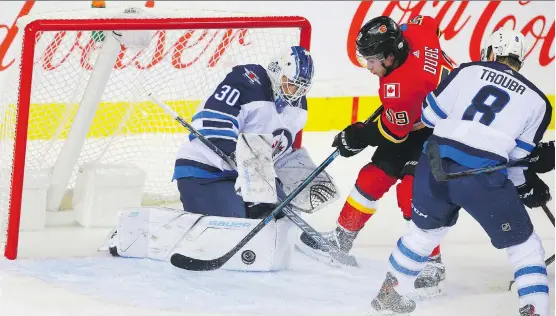  ?? AL CHAREST ?? Winnipeg Jets goalie Laurent Brossoit denies the Calgary Flames’ Dillon Dube from in close Monday during the Jets’ 5-4 overtime victory at Scotiabank Saddledome.