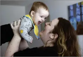  ?? ELLEN M. BANNER — THE SEATTLE TIMES VIA AP ?? Nicole Slemp, a new mother of 7-month-old William, lifts up her son in their home March 14 in Auburn, Wash. Slemp recently quit her job because she and her husband couldn’t find child care they could afford.