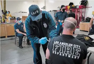  ?? JAE C. HONG THE ASSOCIATED PRESS ?? Firefighte­r Adam Brandos, right, receives his second dose of the COVID-19 vaccine from Michael Perez at a fire station in Los Angeles, Wednesday after the virus killed over 425,000 in the U.S.