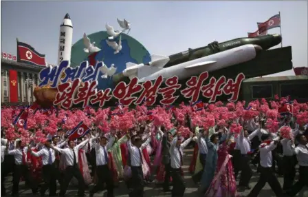  ?? WONG MAYE-E — THE ASSOCIATED PRESS FILE ?? In this Saturday file photo, North Korean men and women wave flags and plastic flowers as a float with model missiles and rockets with words that read “For Peace and Stability in the World” is paraded across Kim Il Sung Square during a military parade...