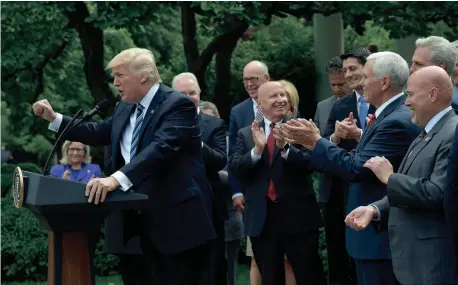  ?? MANDEL NGAN/GETTY IMAGES ?? President Donald Trump, flanked by House GOP lawmakers, speaks in the Rose Garden of the White House following the House vote Thursday on the Republican health bill.