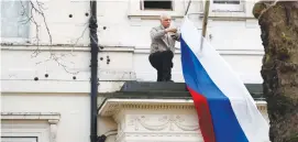  ?? (Phil Noble/Reuters) ?? A MAN REMOVES the flag outside Russia’s Embassy in London yesterday.