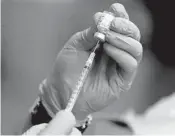  ?? SOUTH FLORIDA SUN SENTINEL
AMY BETH BENNETT/ ?? A CDR Maguire employee fills a syringe with the Pfizer COVID-19 vaccine at John Knox Village.