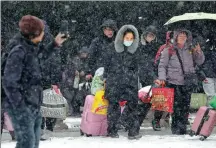  ?? WAN SHANCHAO / FOR CHINA DAILY ?? Passengers exit the Huaibei Railway Station in Anhui province amid snowfall on Sunday.