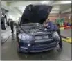  ?? ELAINE THOMPSON — THE ASSOCIATED PRESS ?? Auto technician Anthony Sterns, right, works to replace the coolant expansion tank on a 2011 BMW at the Fat City German Car service shop in Seattle.