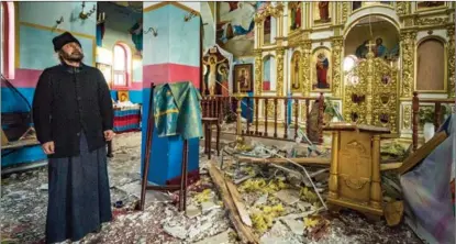  ?? CELESTINO ARCE / NURPHOTO VIA GETTY IMAGES ?? A priest observes the damage on March 26 to a Ukrainian Orthodox Church in Yasnohorod­ka, 50 kilometers west of Kyiv, the capital of Ukraine. The church was hit during fighting as Ukrainian forces tried to stop a Russian advance.