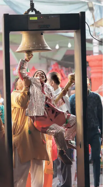  ?? ?? A CHILD DRESSED as a langur rings the temple bell with a little help, at the Bada Hanuman temple situated just outside the old walled city of Amritsar.