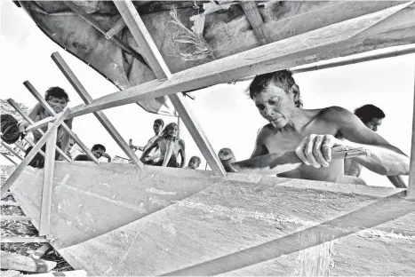  ?? MACKY LIM ?? MASTER BUILDERS. Using just a bolo and mallet, Badjao men craft a boat in their community at Badjao Village in Barangay Matina Aplaya Seaside 2 in Davao City yesterday afternoon. A boat takes 15-20 days to build, say the master boat builders.