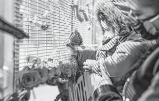  ?? Aaron Nesheim / New York Times ?? Cayden Totushek affixes a rose to a new art piece by Visual Black Justice, placed outside the court building in Minneapoli­s where Derek Chauvin is on trial in the death of George Floyd.