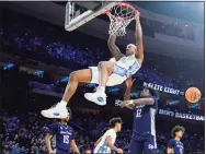  ?? Chris Szagola / Associated Press ?? North Carolina’s Armando Bacot, left, hangs on the rim after a dunk past St. Peter’s Clarence Rupert during the first half Sunday.