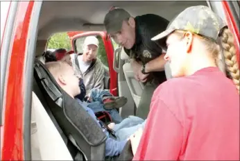  ?? Times photograph by Annette Beard ?? Seth Wilkerson, 5, laughs as Benton County Sheriff’s Sgt. Tom See asks him if he wants to be like Lightning Mcqueen and go “Kerchow!” Seth and his brother, Evan, 3 1/2, were shown how to safely and snugly buckle up in their new car seats. The boys are...