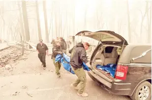  ??  ?? PARA pegawai Sherif Daerah Yuba dan Butte memasukkan mayat ke dalam kereta mayat sejurus ditemui di sebuah kediaman yang hangus di Paradise, California kelmarin.