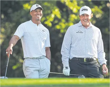  ?? AP ?? Tiger Woods, left, and Phil Mickelson share a laugh on the 11th tee box while playing a practice round at Augusta National.