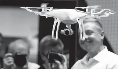  ?? REUTERS ?? Visitors take pictures of a DJI Phantom 4 Quadcopter drone at the Photokina, the world’s largest fair for imaging in Cologne, Germany, in September.