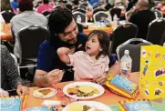  ?? ?? Nathan Briones, 2, sits on the lap of his father, Juan Briones, during the dinner. An estimated 25,000 people came to the Convention Center for the event.