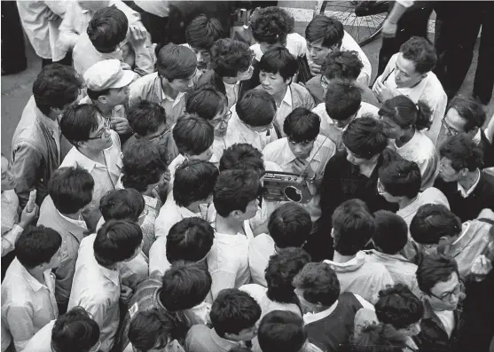 ??  ?? Crowds gather to listen to the news from a radio at People’s Square. In the 1980s, radio was still a major news source for people to get informatio­n. — Xu Weimin