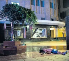  ?? AFP ?? A man sleeps on the pavement on Nanjing East Road, a pedestrian street filled with shoppers and tourists during the day, to escape the heat of apartments in Shanghai.