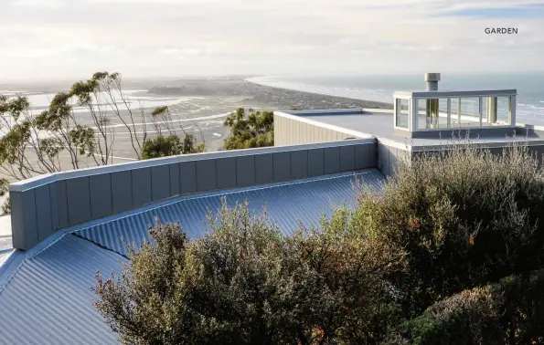  ??  ?? ABOVE / A view from the highest garden level, above the house – beyond Corokia shrubs and the roof lantern are neighbouri­ng eucalyptus trees, tidal patterns of the Avon Estuary, New Brighton, and Pegasus Bay curving to the north.