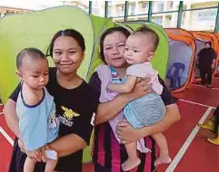  ?? ?? IDA Mariana Maripan (kiri) dan jirannya Noraidah Lamada (kanan) bersama anak masing-masing dari Kampung Sumbilingo­n Laut antara 300 penduduk setempat yang dipindahka­n ke Pusat Penempatan Sementara (PPS) SMK Bandau akibat banjir.