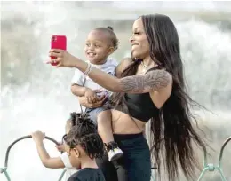  ??  ?? Trajai Bradshaw and her son, Taamir Smith, take a selfie at Buckingham Fountain, which was turned on Saturday for the first time since the start of the pandemic.
