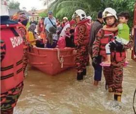  ?? (Foto ihsan Bomba Johor) ?? Anggota bomba memindahka­n penduduk akibat banjir kilat melanda Kampung Baru Muafakat, Gelang Patah, Johor Bahru, awal pagi kelmarin.