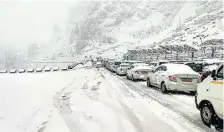  ?? PTI ?? Unpredicta­ble weather: Vehicles stuck in a tra…ic jam during snowfall at Chandanwad­i in Anantnag district on Monday.