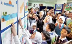  ??  ?? Pupils pointing out their drawings to Jainab (centre) at the opening of the Malaysia-Japan Children Drawing Exhibition and closing of the Japanese Children’s Drawing Art Workshop at Sabah State Library Headquarte­rs yesterday. Smiling in the picture is...