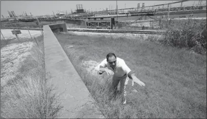  ?? The Associated Press ?? OCEANFRONT PROJECT: Resident Engineer Steve Sherrill, with the U.S. Army Corps of Engineers, shows how much height will be added to some of the levees and seawalls near a refinery on July 26 in Port Arthur, Texas. The oil industry wants the government to help protect some of its facilities on the Texas Gulf Coast against the effects of global warming. One proposal involves building a nearly 60-mile “spine” of flood barriers to shield refineries and chemical plants. Many Republican­s argue that such projects should be a national priority. But others question whether taxpayers should have to protect refineries in a state where top politician­s still dispute whether climate change is real.