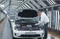  ??  ?? An employee inspects a Volkswagen e-Golf electric automobile in the light tunnel inside the Volkswagen AG factory in Dresden, Germany. China is one of Volkswagen’s most important markets.